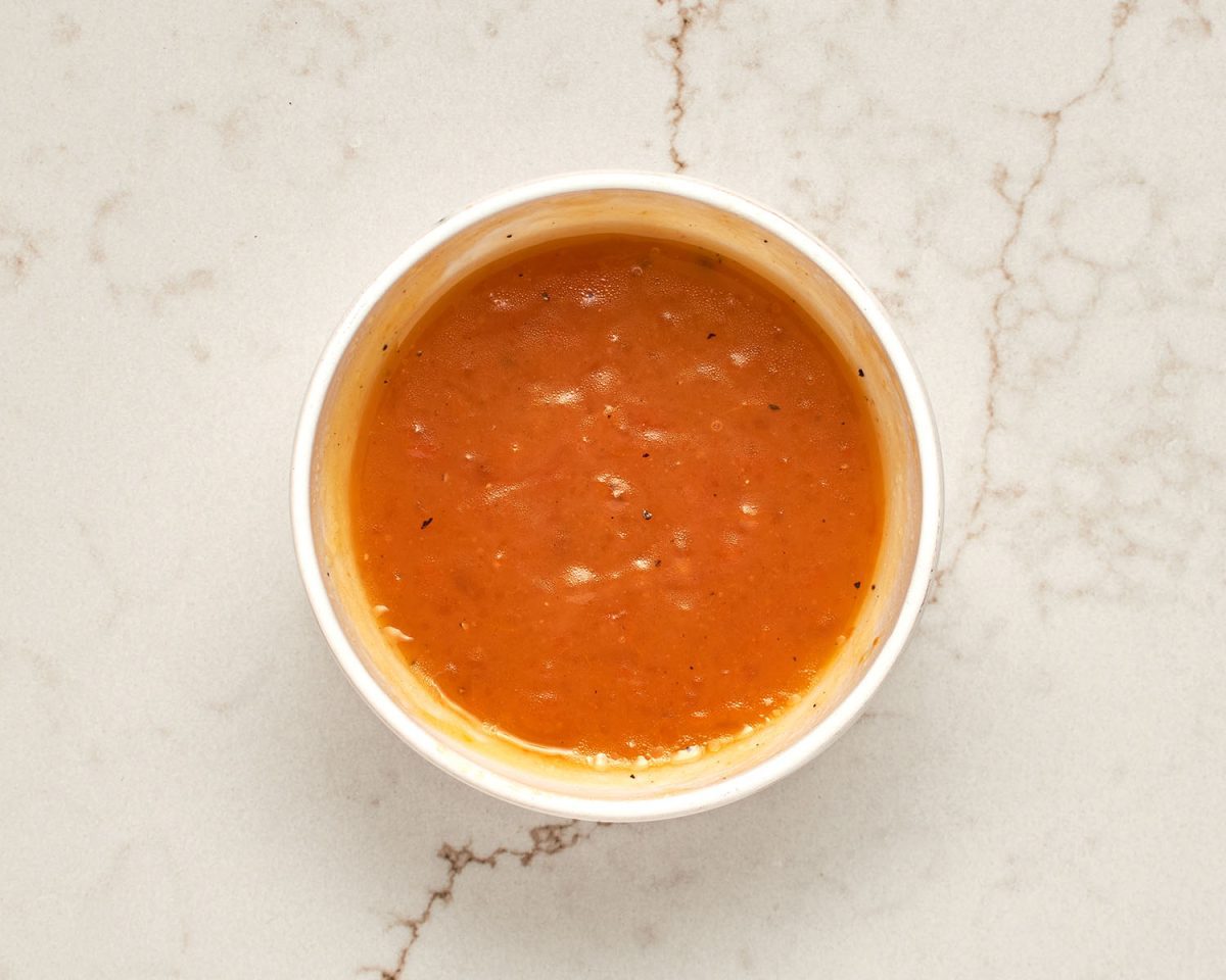 apricot preserves, olive oil, vinegar, salt, and black pepper combined into apricot sauce in white bowl