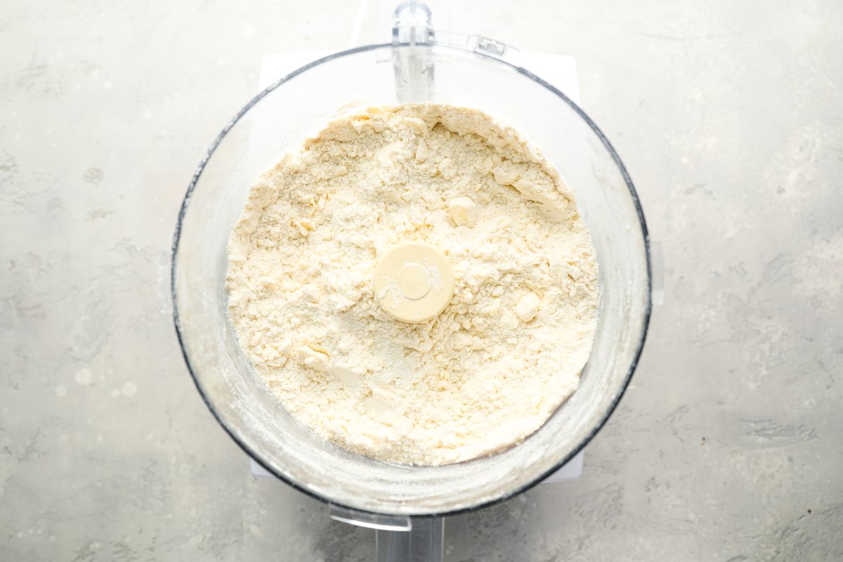 butter added to flour, sugar, salt, and baking powder in bowl of food processor