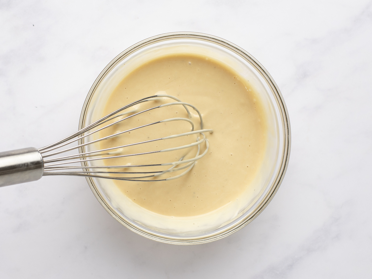 mayonnaise, mustard, black pepper, honey, and vinegar being whisked together in small bowl