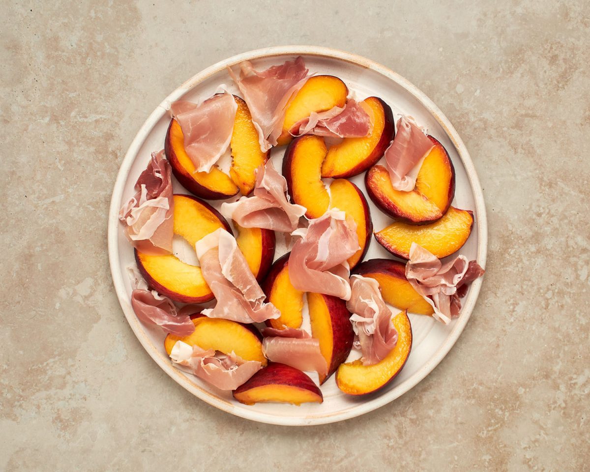 peaches and prosciutto on round white platter