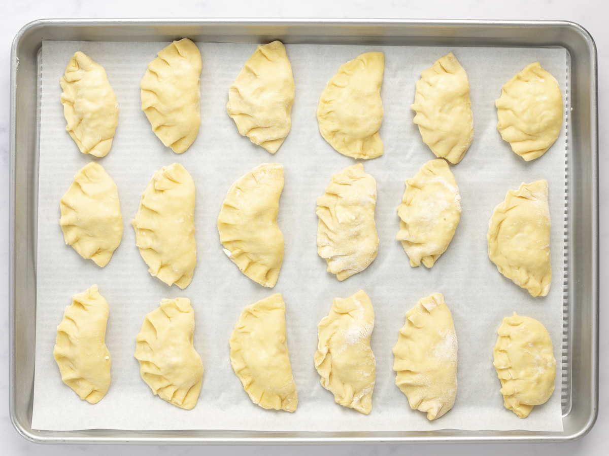 filled, folded, and sealed  pierogi on baking sheet 