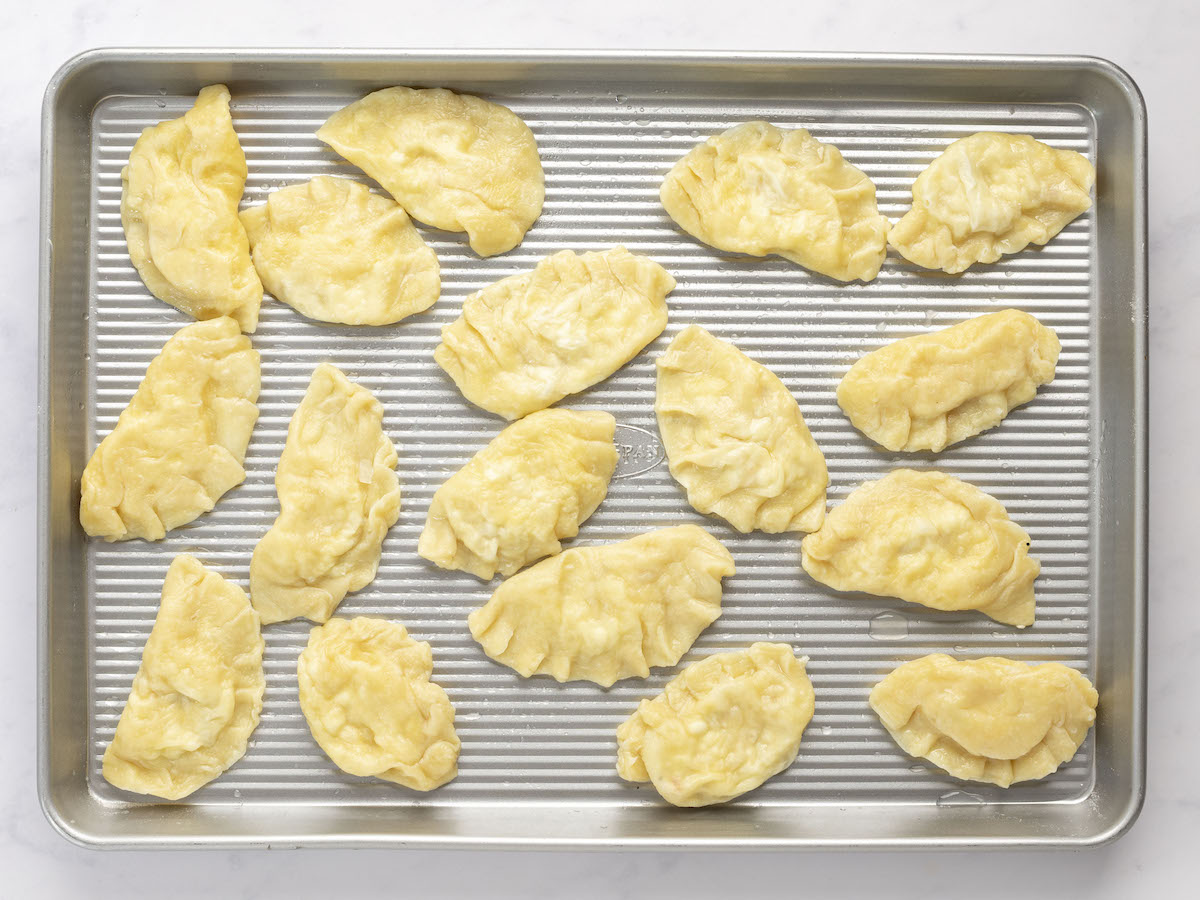 boiled pierogi with a light coating of oil on baking sheet