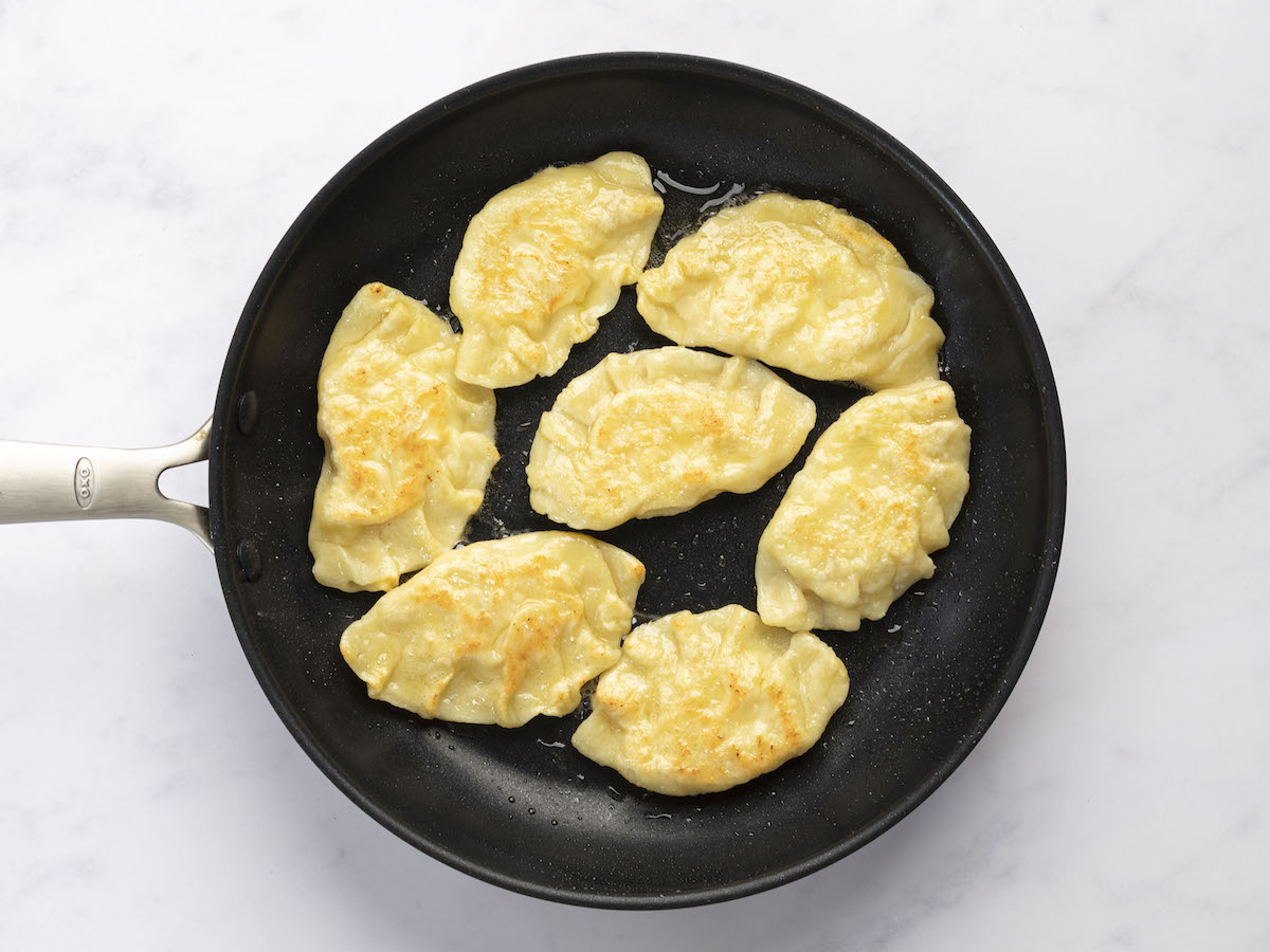 pierogi cooking in a skillet in a single layer