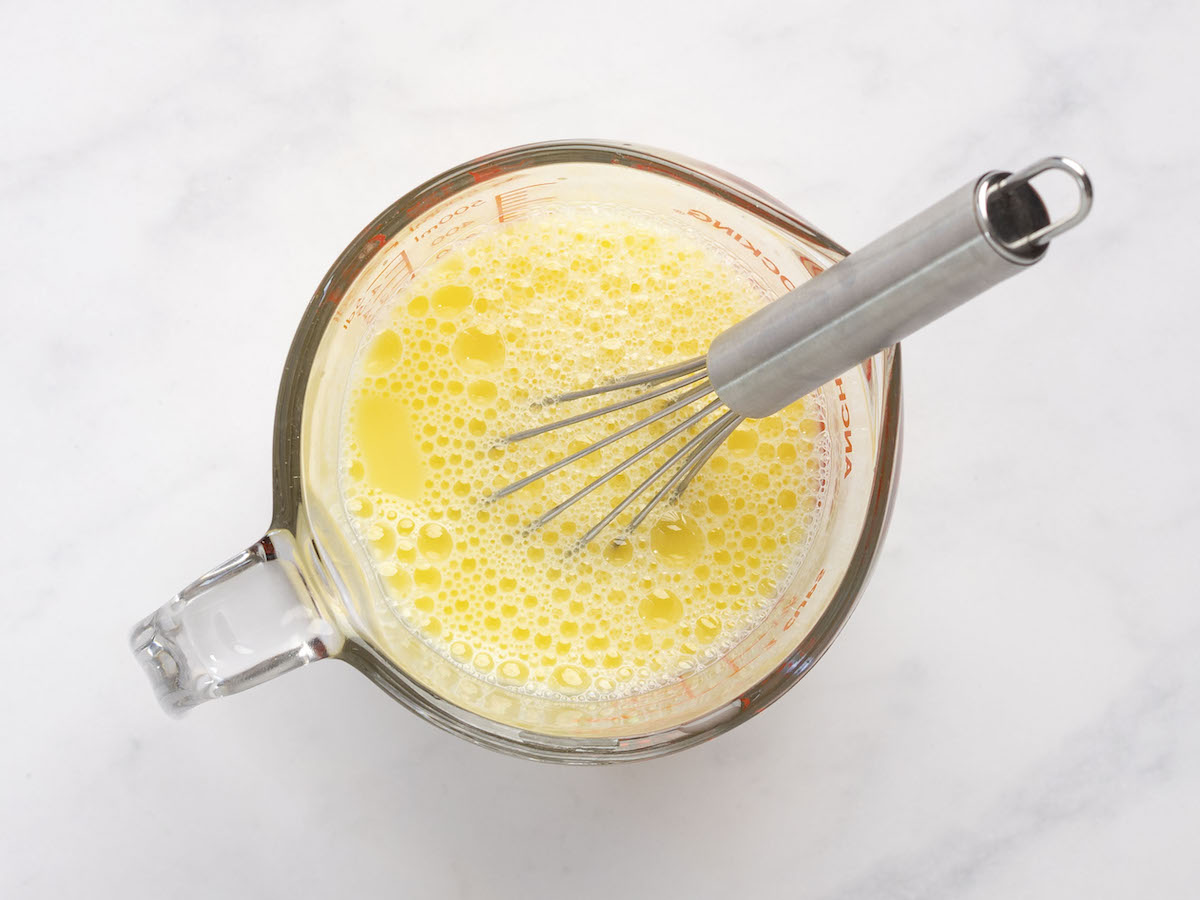 water and eggs being whisked in liquid measuring cup