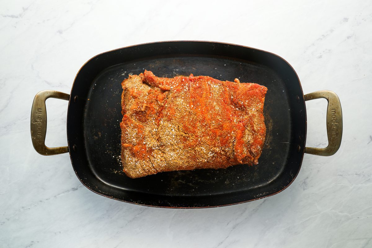 pork butt coated with spice rub in roasting pan