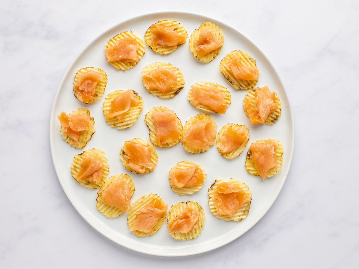 each potato chip topped with folded piece of salmon