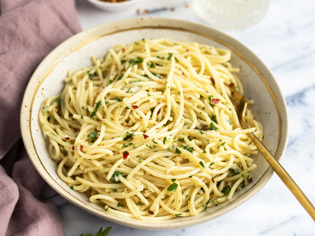 spaghetti aglio e olio in large white serving bowl with fork