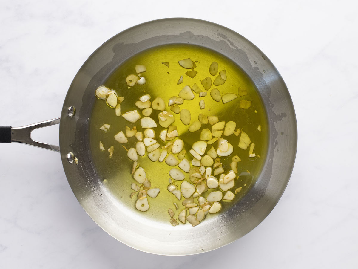 large skillet with olive oil and golden cooked garlic slices