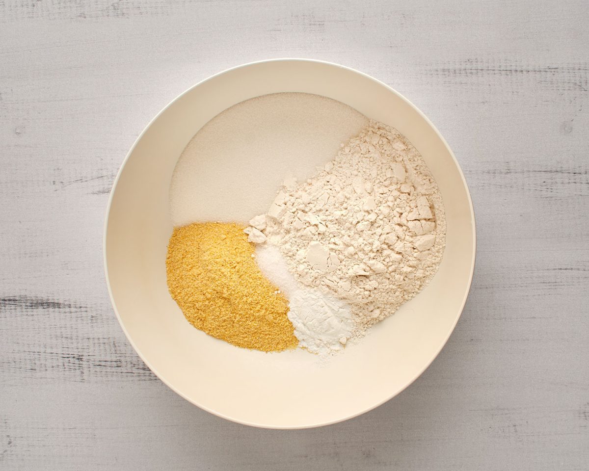 flour, cornmeal, sugar, baking powder, and salt in white mixing bowl