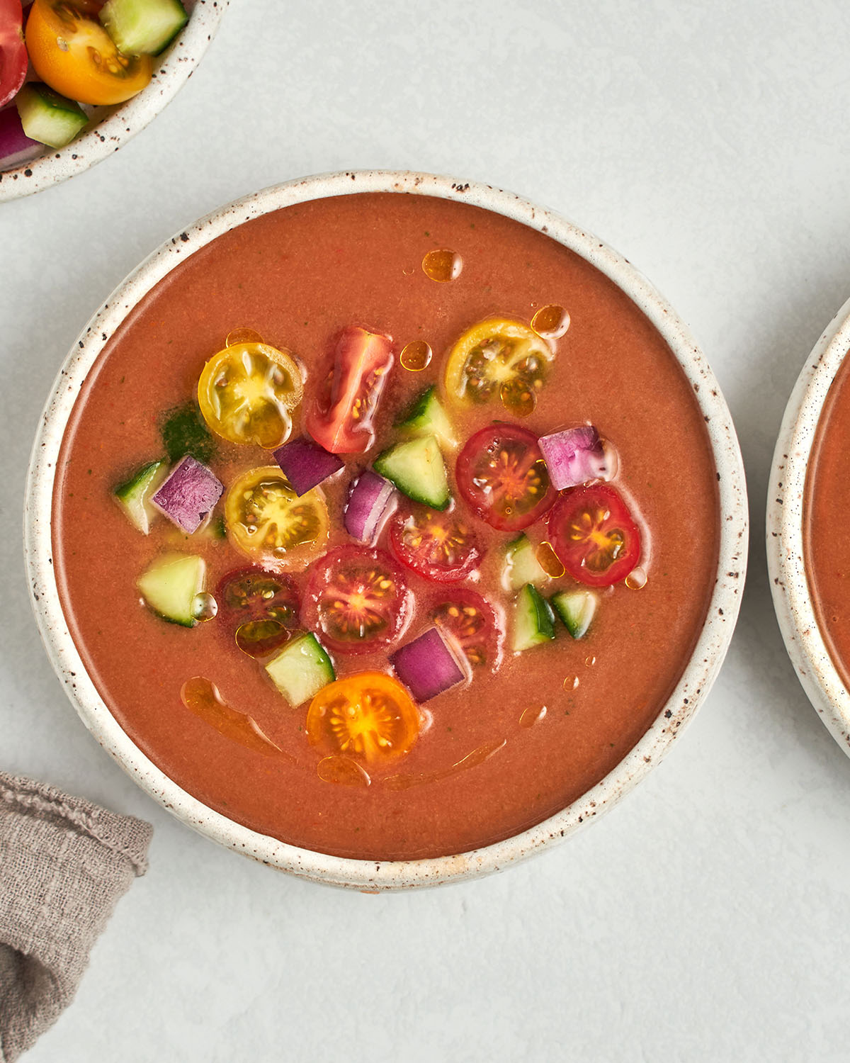 serving bowl with gazpacho topped off with diced cucumbers and tomatoes