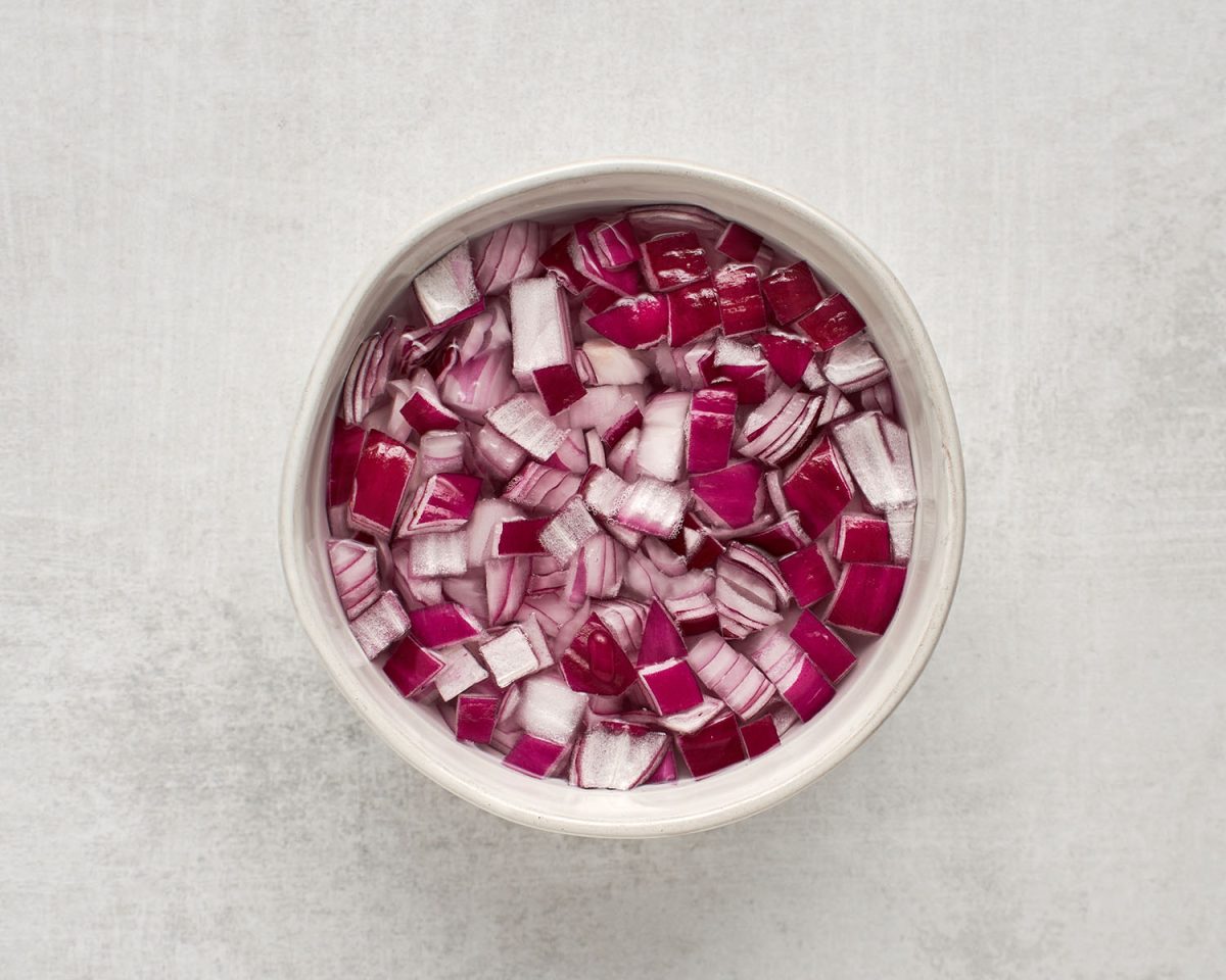 diced red onion soaking in  water in small white bowl