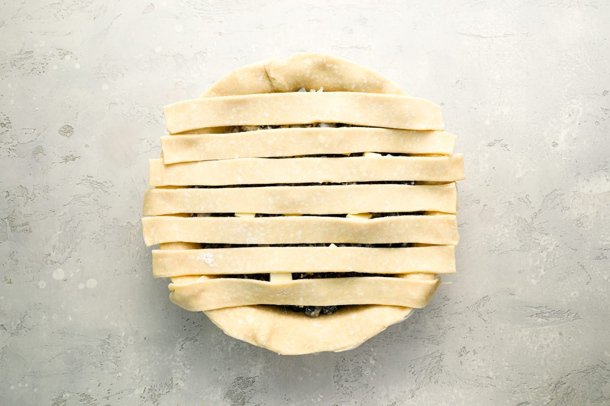 7 dough strips laid horizontally over pie filling