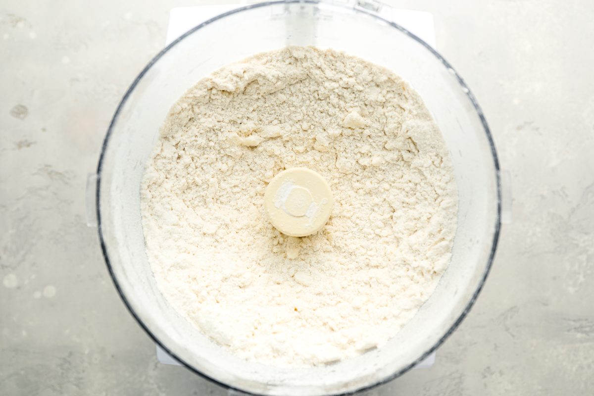 bowl of food processor with butter mixed into flour mixture