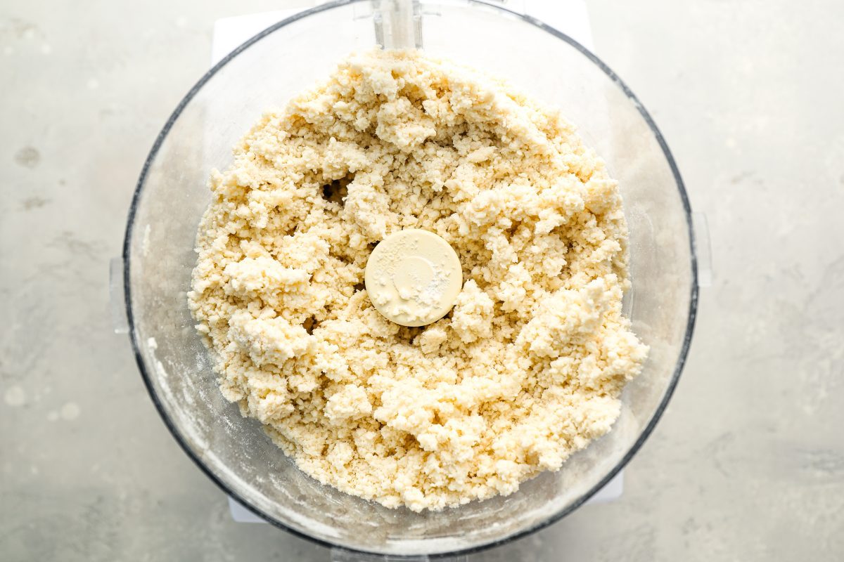 food processor bowl with crumbly dough mixture