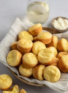 Brazilian cheese bread in basket with linen napkin and glass of wine