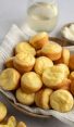 Brazilian cheese bread in basket with linen napkin and glass of wine