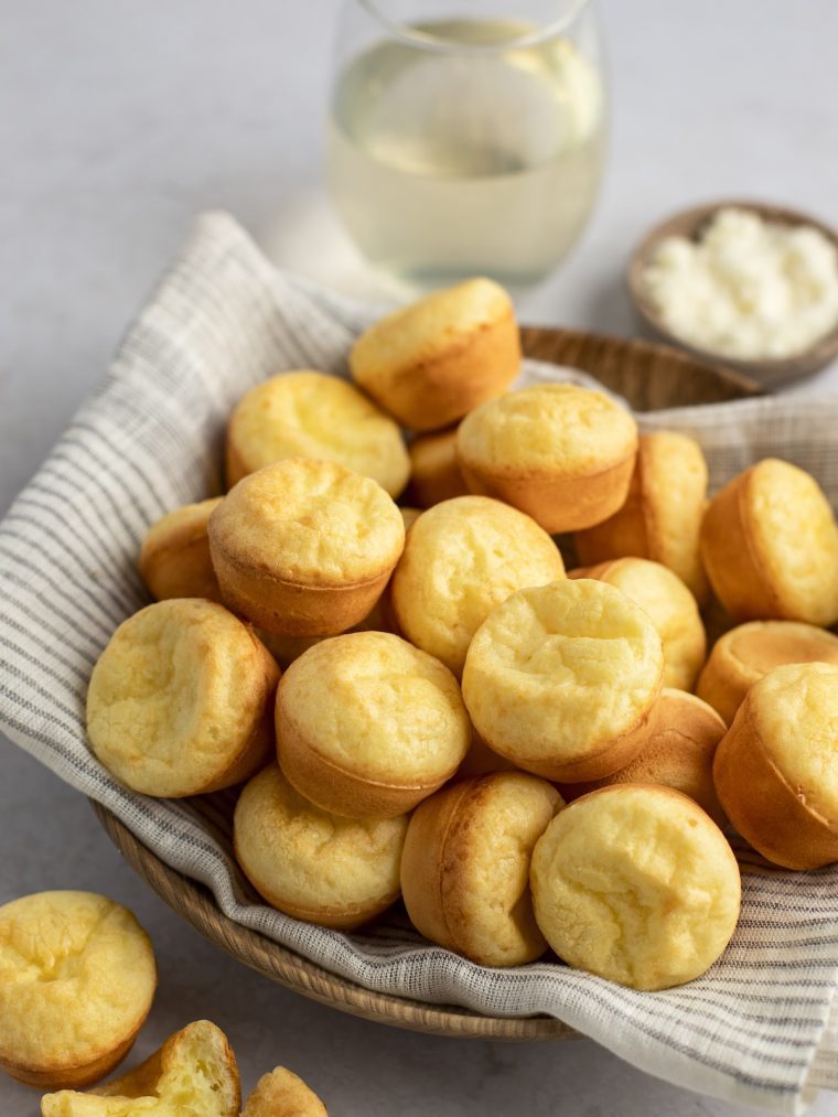 Brazilian cheese bread in basket with linen napkin and glass of wine