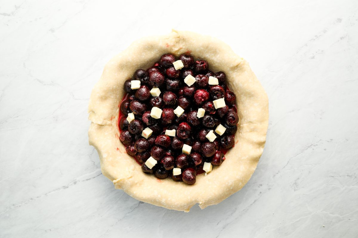 cherry filling in pie crust dotted with butter