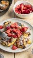 confectioner sugar dusted kaiserschmarrn on white plate with strawerry pieces scattered on top