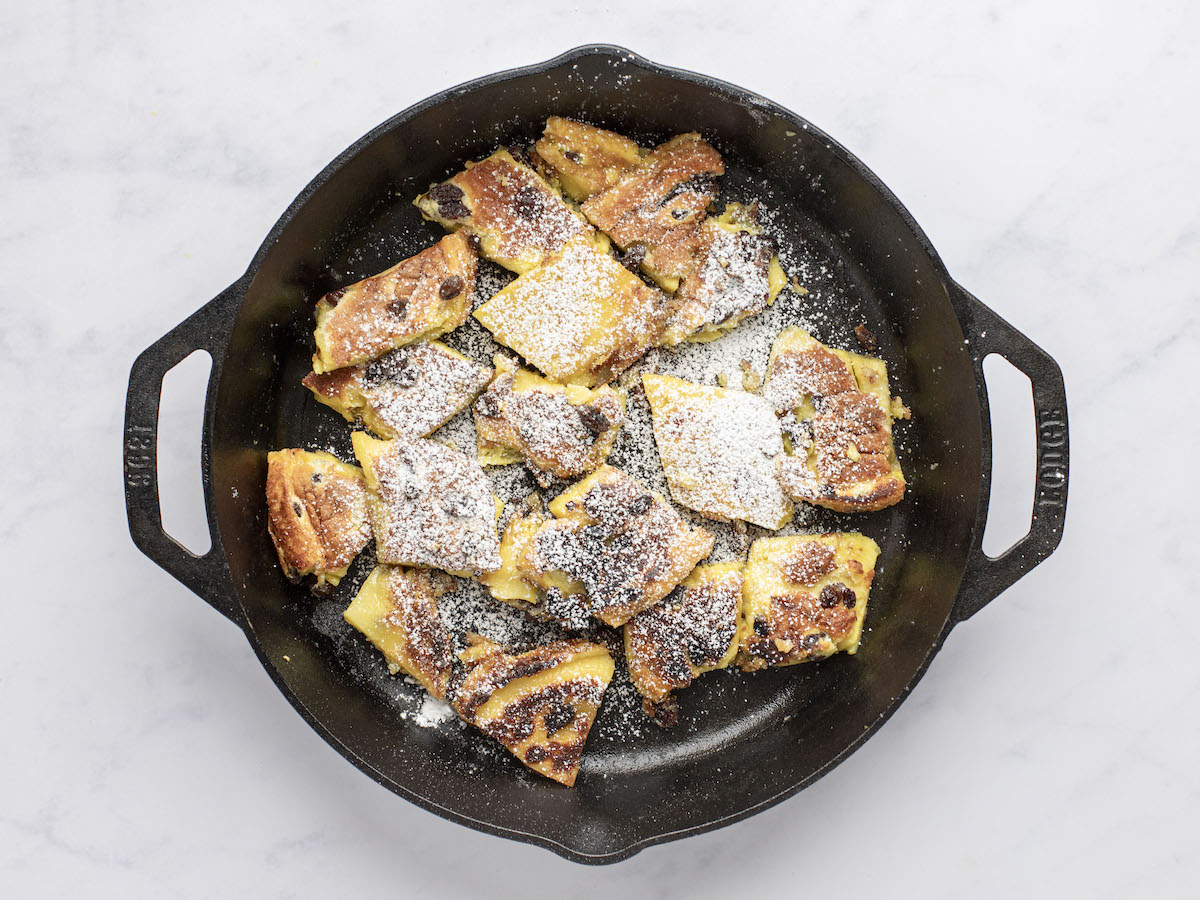 caramelized kaiserschmarrn in non-stick skillet dusted with confectioners' sugar