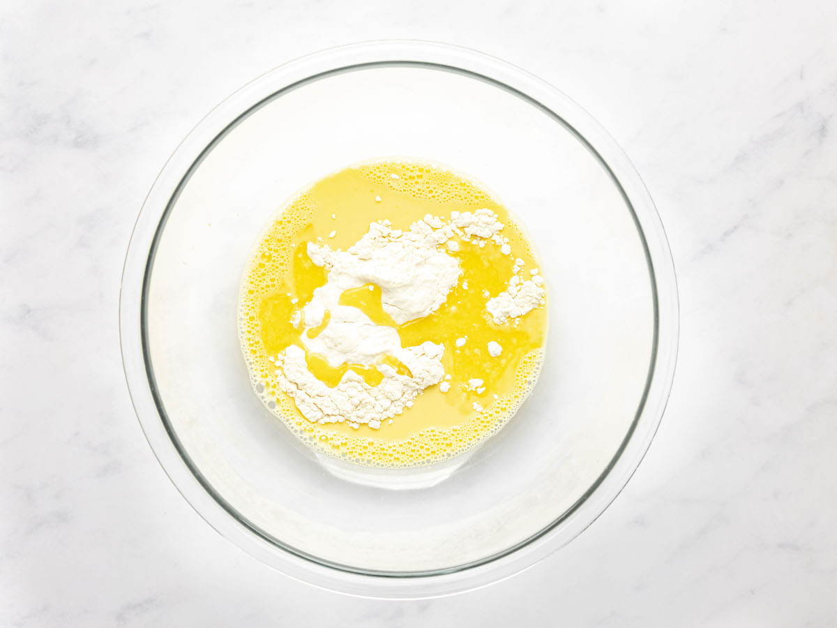 large bowl with flour added to egg yolks, milk, vanilla, and rum