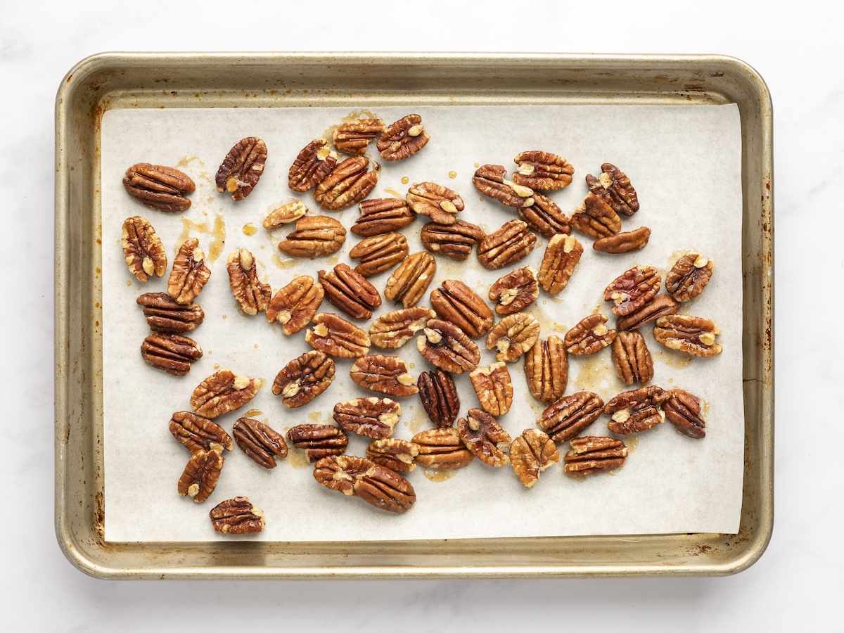 maple coated pecans on parchment-lined baking sheet