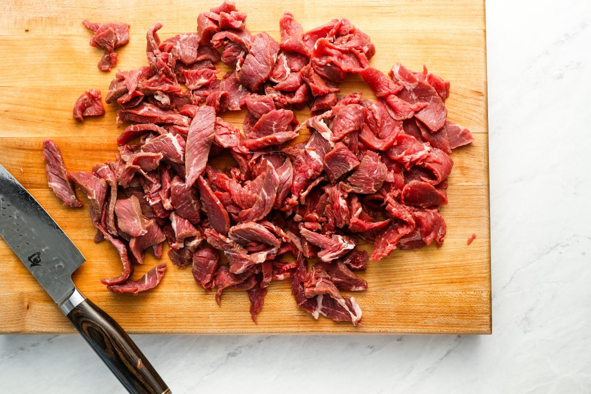 thinly sliced sirloin steak on large wood cutting board