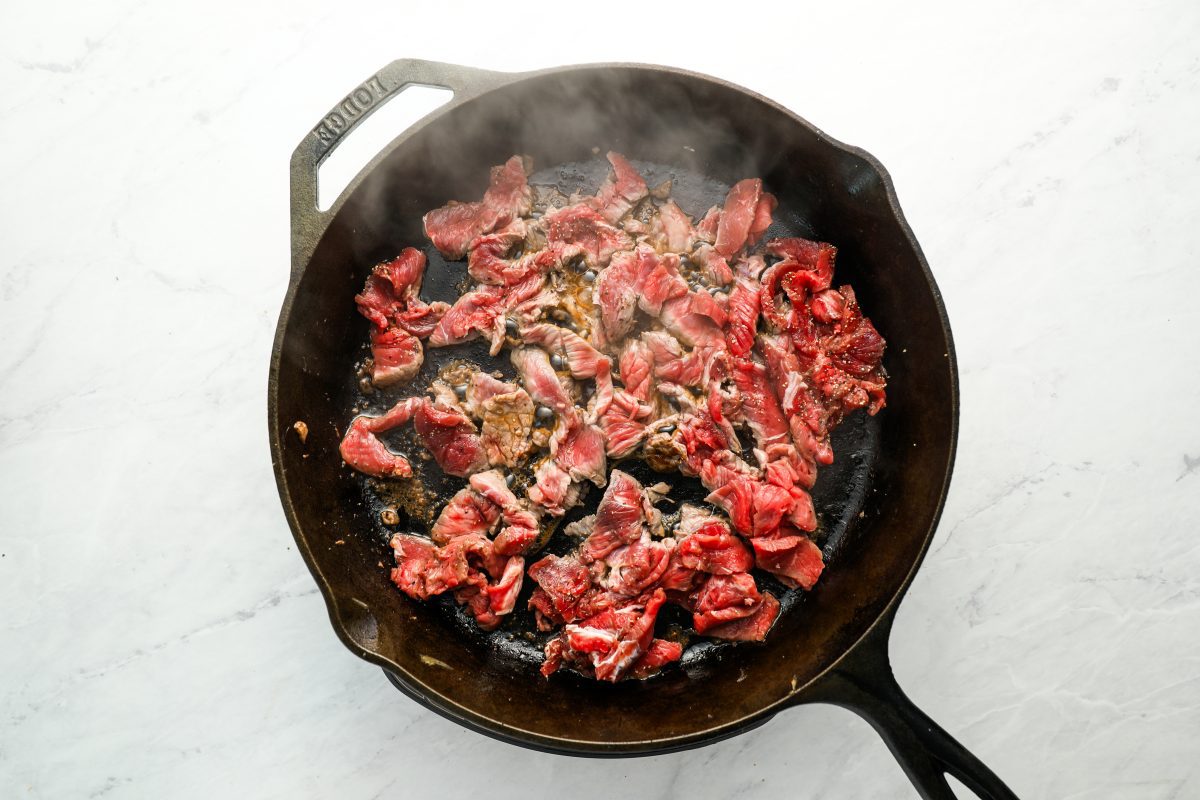 half of the diced meat cooking in large cast iron skillet