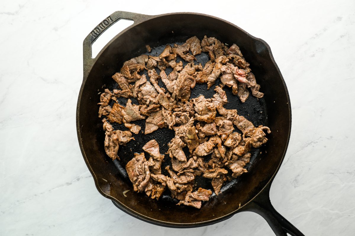 diced steak fully cooked in large cast iron skillet