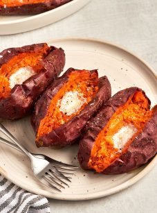 baked sweet potatoes with butter on platter with dish towel