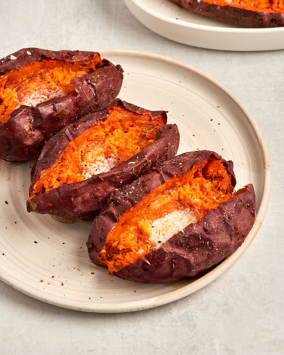 baked sweet potatoes with butter on platter with dish towel