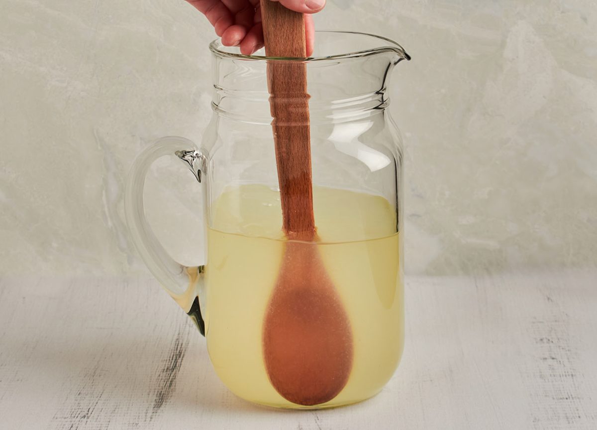 stirring lemonade in pitcher with wooden spoon