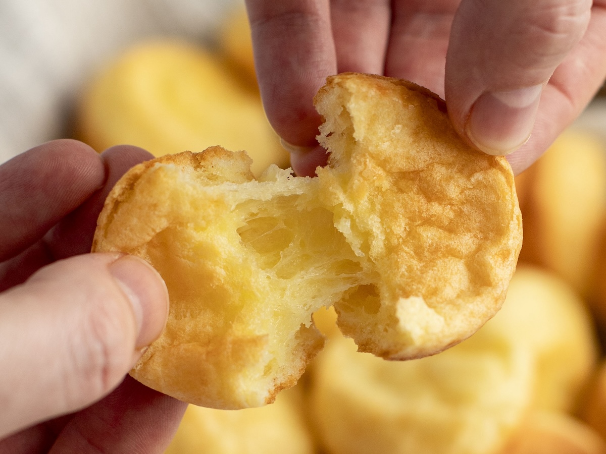 pulling apart Brazilian cheese bread to reveal gooey center