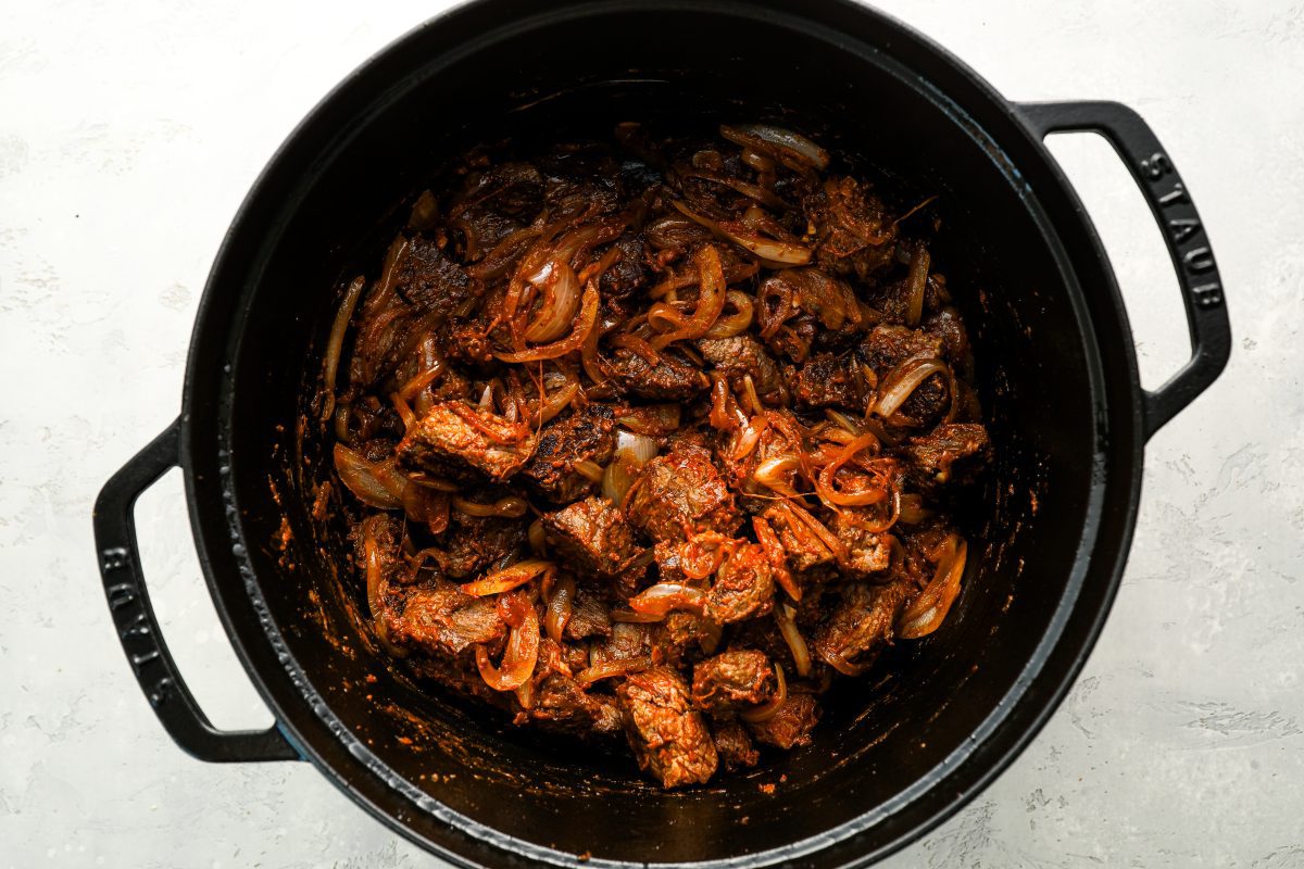 dutch oven with beef and flour added to onion mixture