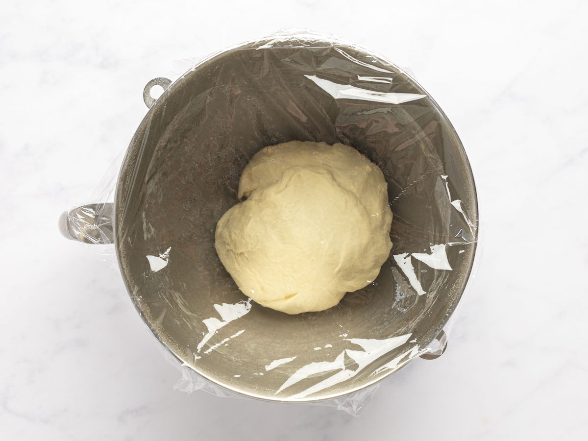 dough ball in mixing bowl covered with plastic wrap