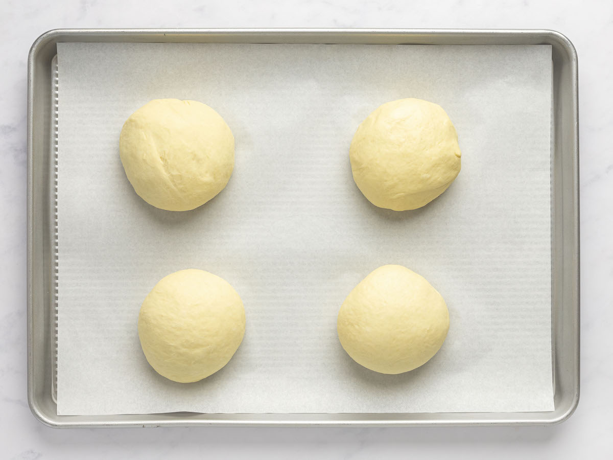 4 dough balls on parchment-lined baking sheet