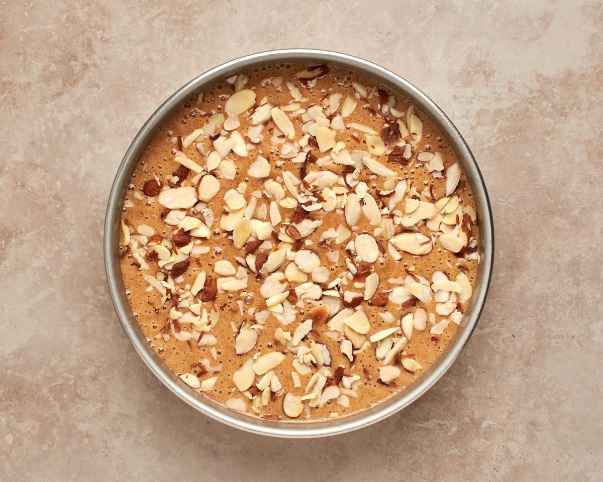 honey cake batter topped with sliced almonds in cake pan