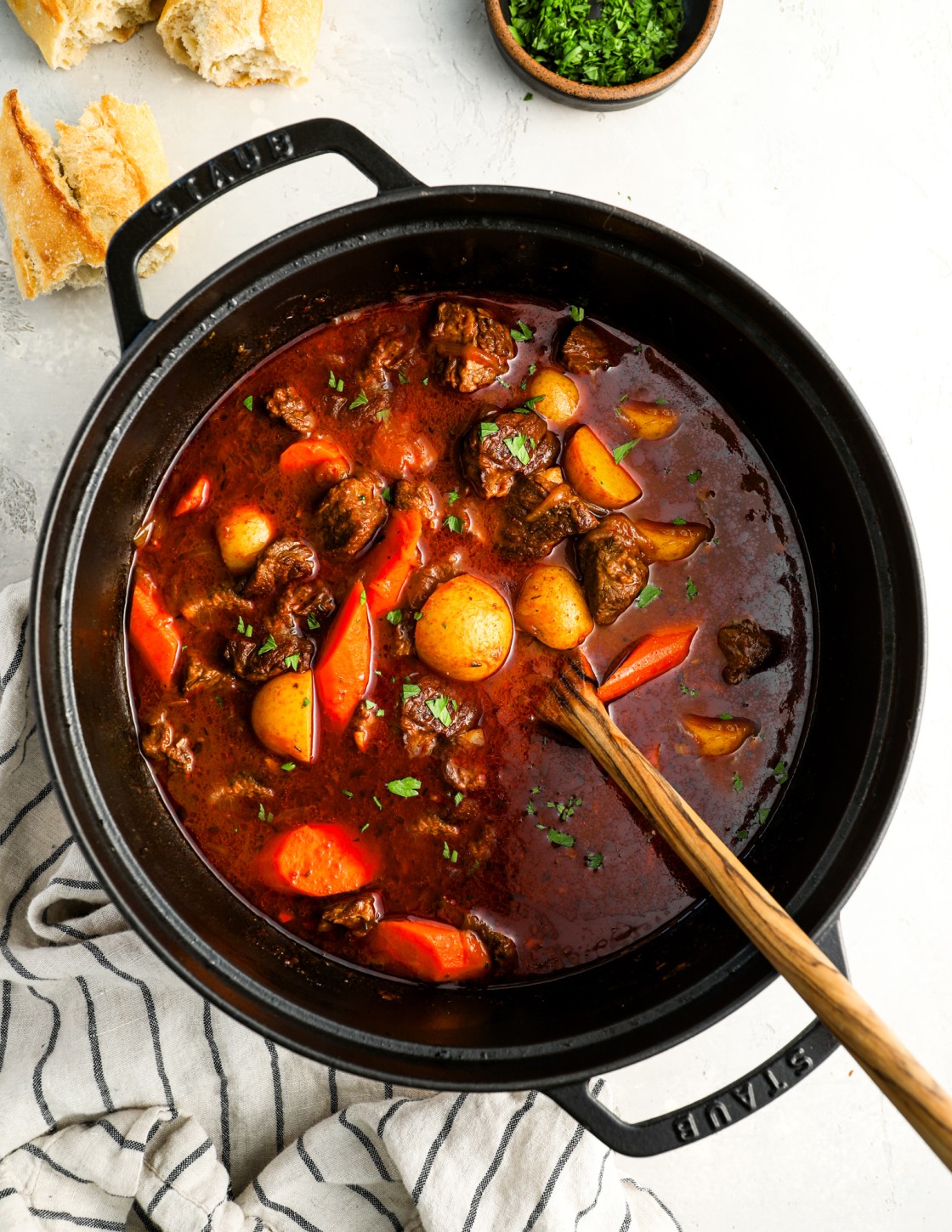 Hungarian goulash in Dutch oven with crusty bread and bowl of parsley