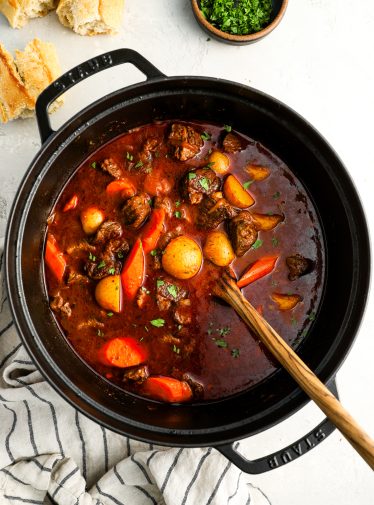 Hungarian goulash in Dutch oven with crusty bread and bowl of parsley