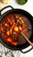 Hungarian goulash in Dutch oven with crusty bread and bowl of parsley