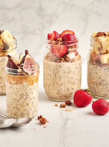 4 jars of overnight oats topped with a variety of fresh fruit and granola