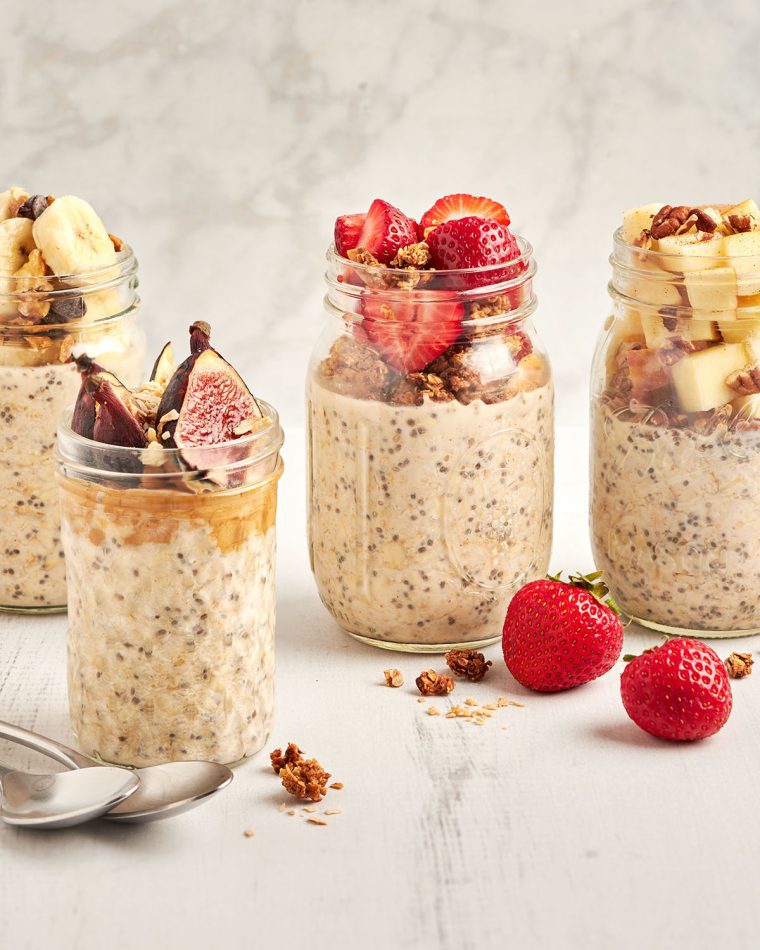 4 jars of overnight oats topped with a variety of fresh fruit and granola