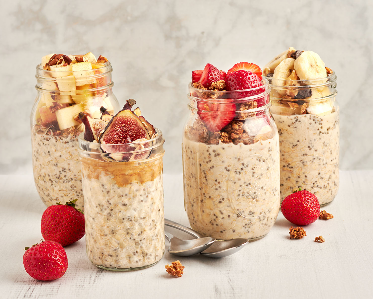 4 jars of overnight oats topped with a variety of fresh fruit and granola