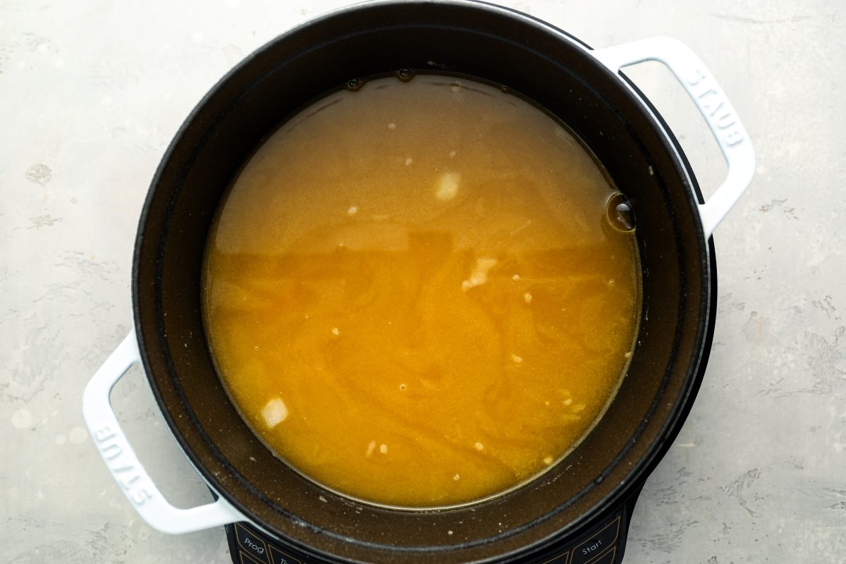 chicken broth in dutch oven with carrots, onions, and garlic