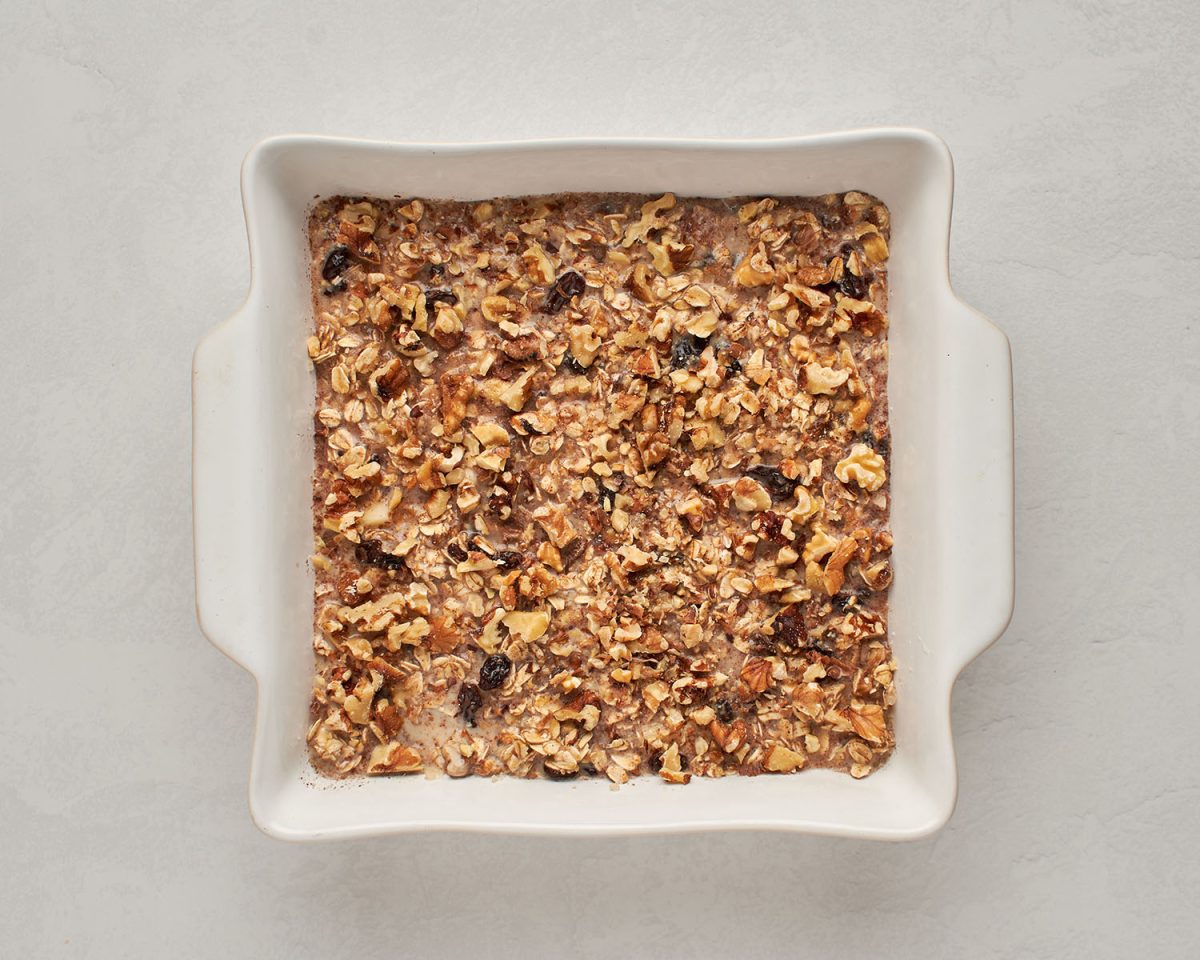 oat mixture poured over apples in dish with nuts sprinkled on top