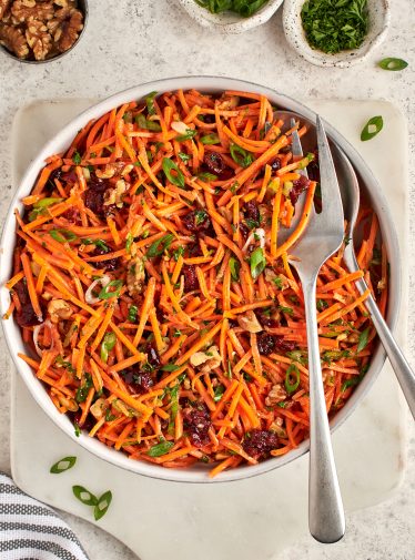 carrot slaw with cranberries, walnuts, and citrus vinaigrette in serving bowl.