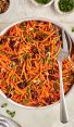 carrot slaw with cranberries, walnuts, and citrus vinaigrette in serving bowl.