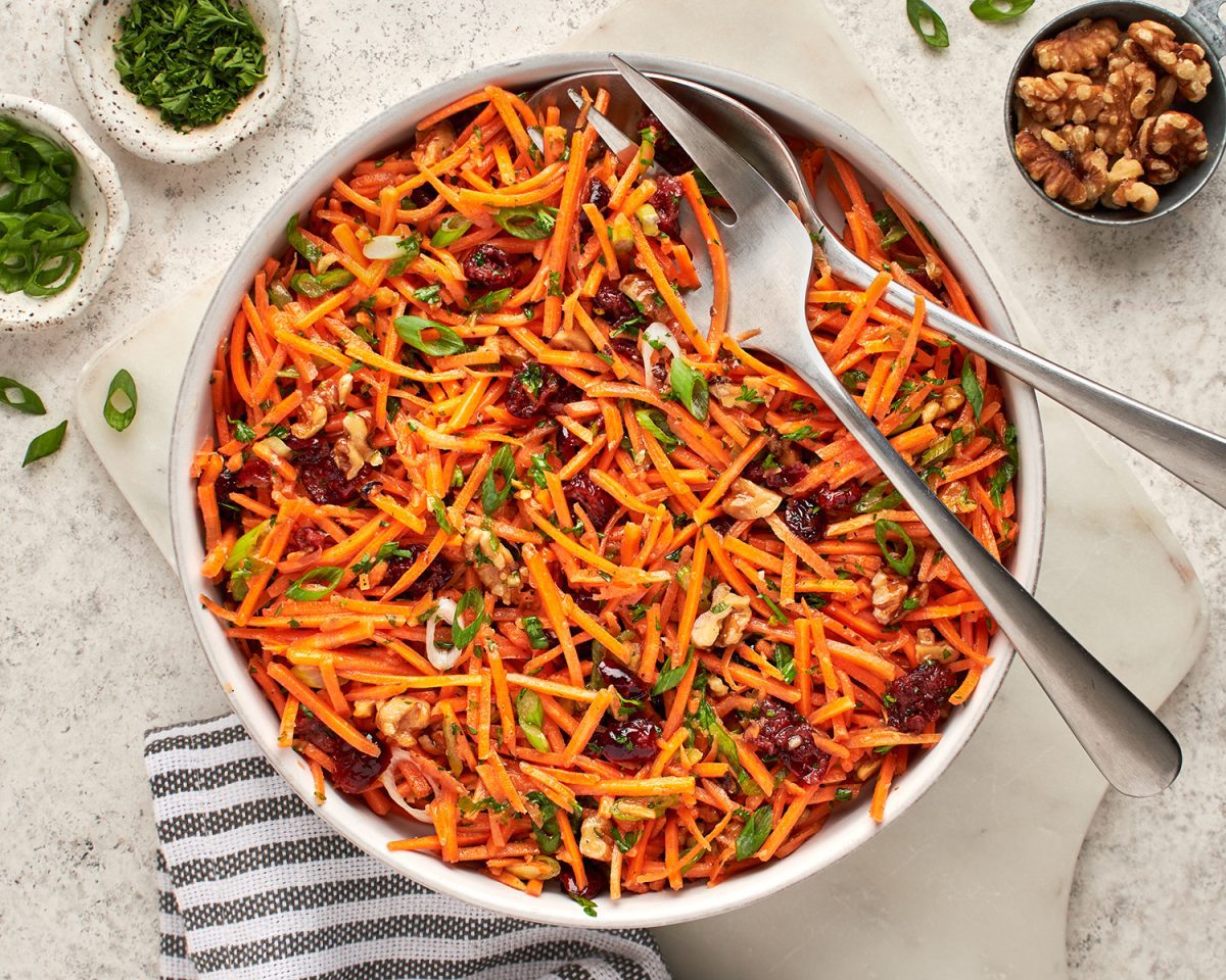 bowl of carrot slaw with cranberries and walnuts  with cloth napkin