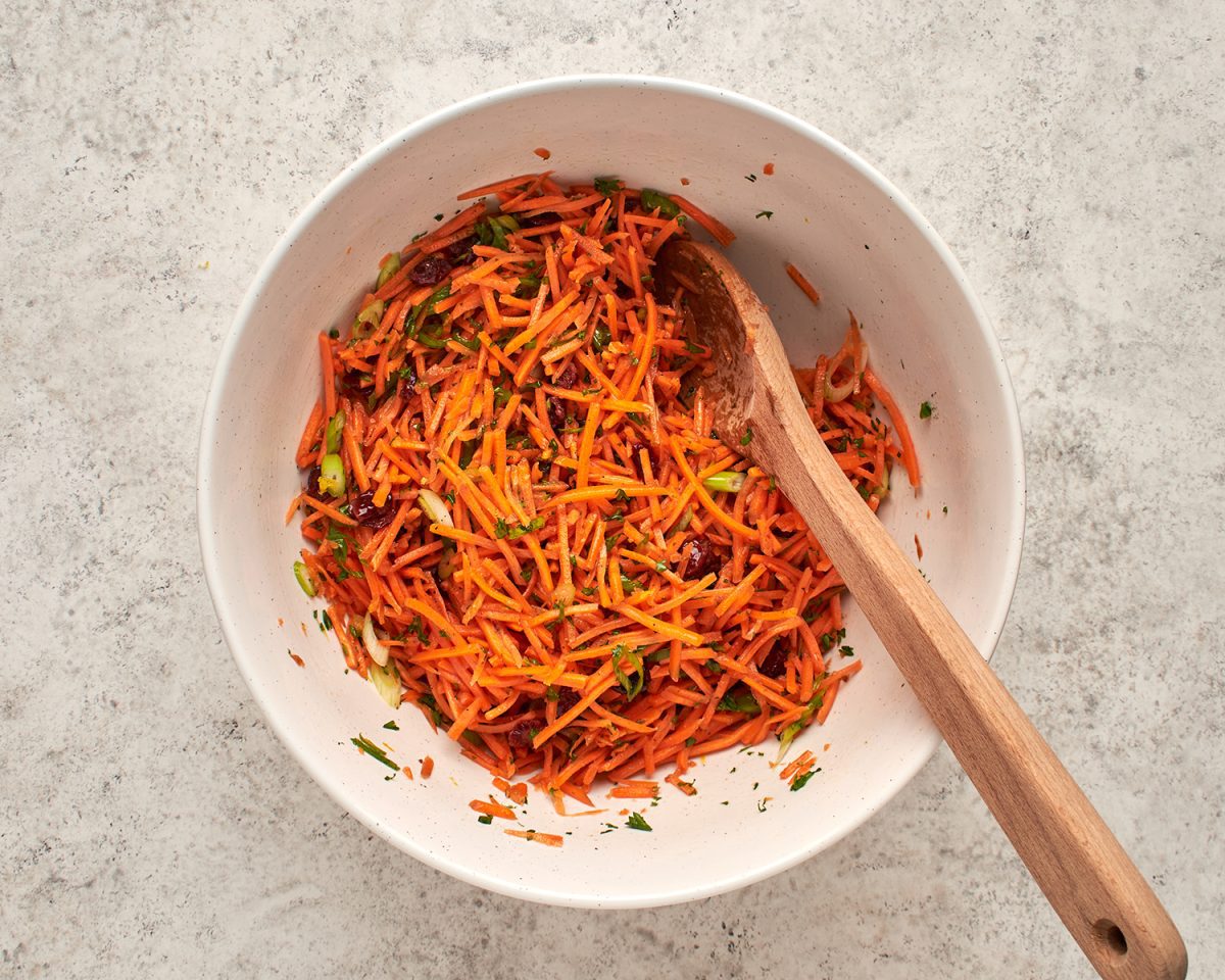 tossed carrot slaw in bowl in wooden spoon