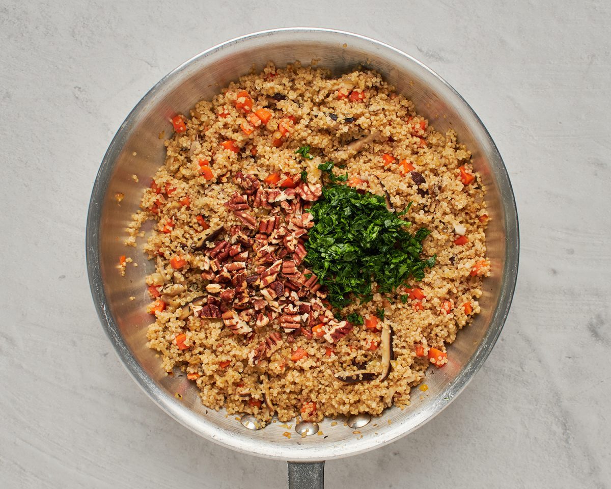 adding the pecans and parsley to the quinoa and vegetable mixture